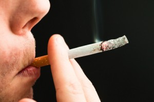 Man smoking a cigarette against a black background